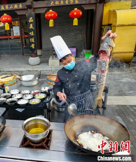 招牌菜铁锅炖大鱼下锅烹饪。　王耀 摄